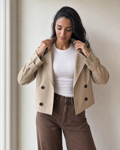settling the collar of the beige cropped trench coat